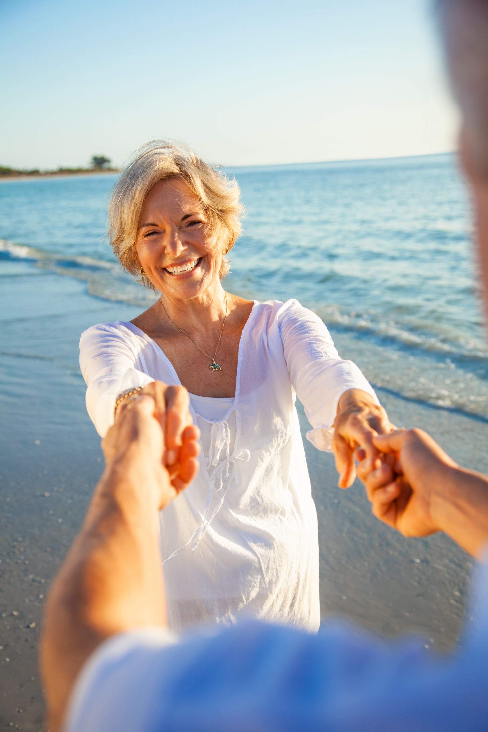 Couple holding hands on beach with blue sky