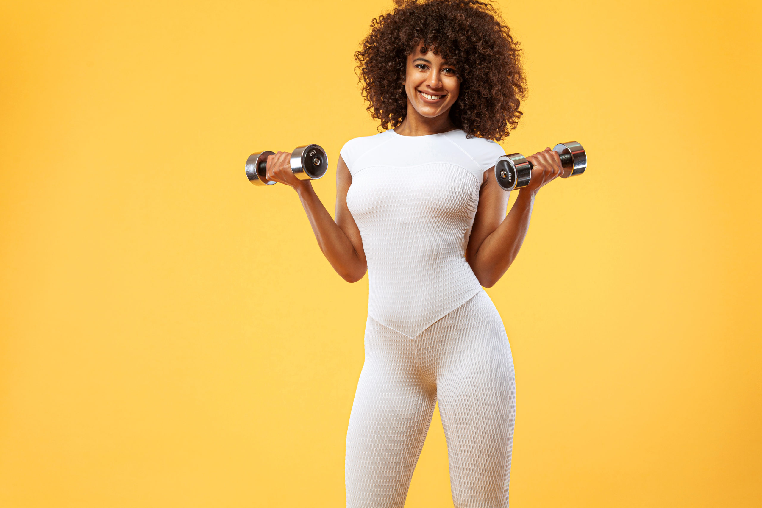 Sporty fit woman, athlete with dumbbells makes fitness exercising on white background. Fitness and workout motivation.