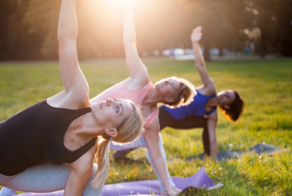 3 Women Exercising Yoga in Park