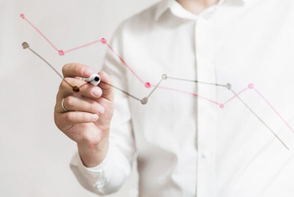 business person wearing white shirt hand preparing a graph report on glass board with marker